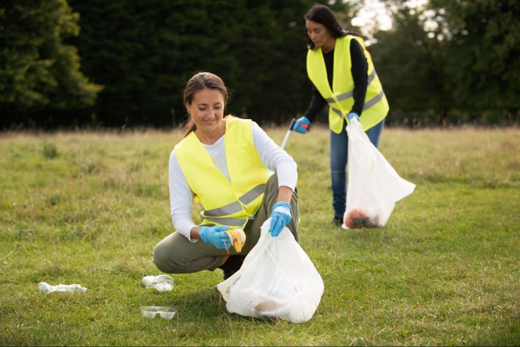 Empreendedorismo social - duas mulheres praticando trabalho voluntário de coleta de lixo em um parque