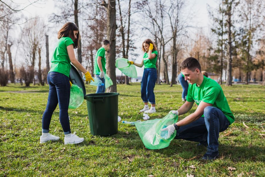 O que é impacto social- grupo de voluntários em ação de coleta de lixo em um parque.